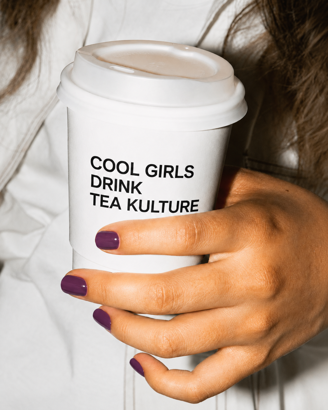 Hand holding a white Tea Kulture cup that reads 'Cool Girls Drink Tea Kulture'